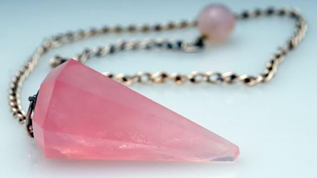 A pink crystal is sitting on top of a chain.